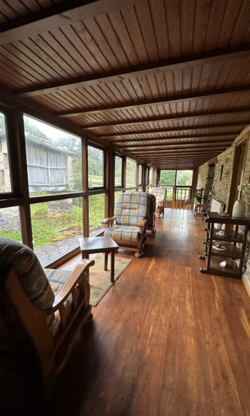 Butacas junto a los ventanales de la galería, con suelo y techo de madera.