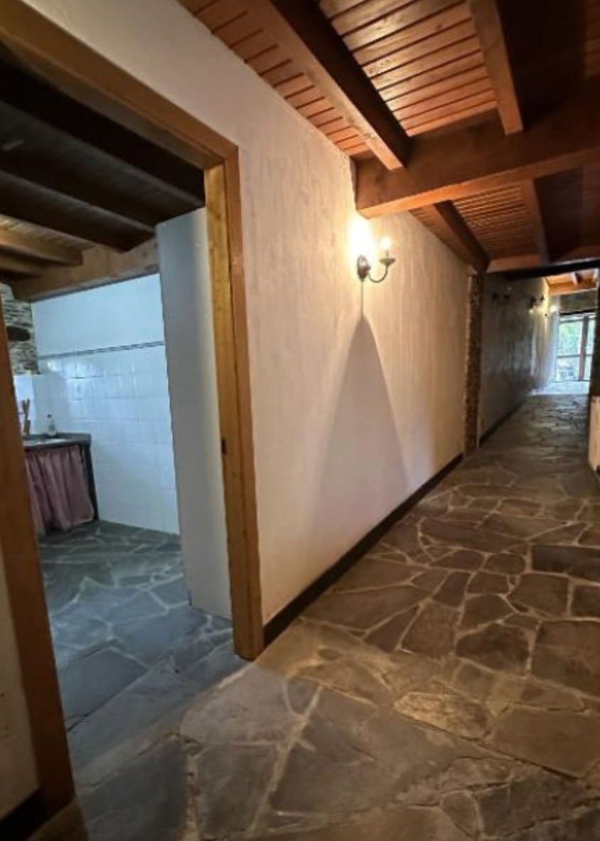 Pasillo con suelo de piedra y acceso a la cocina.