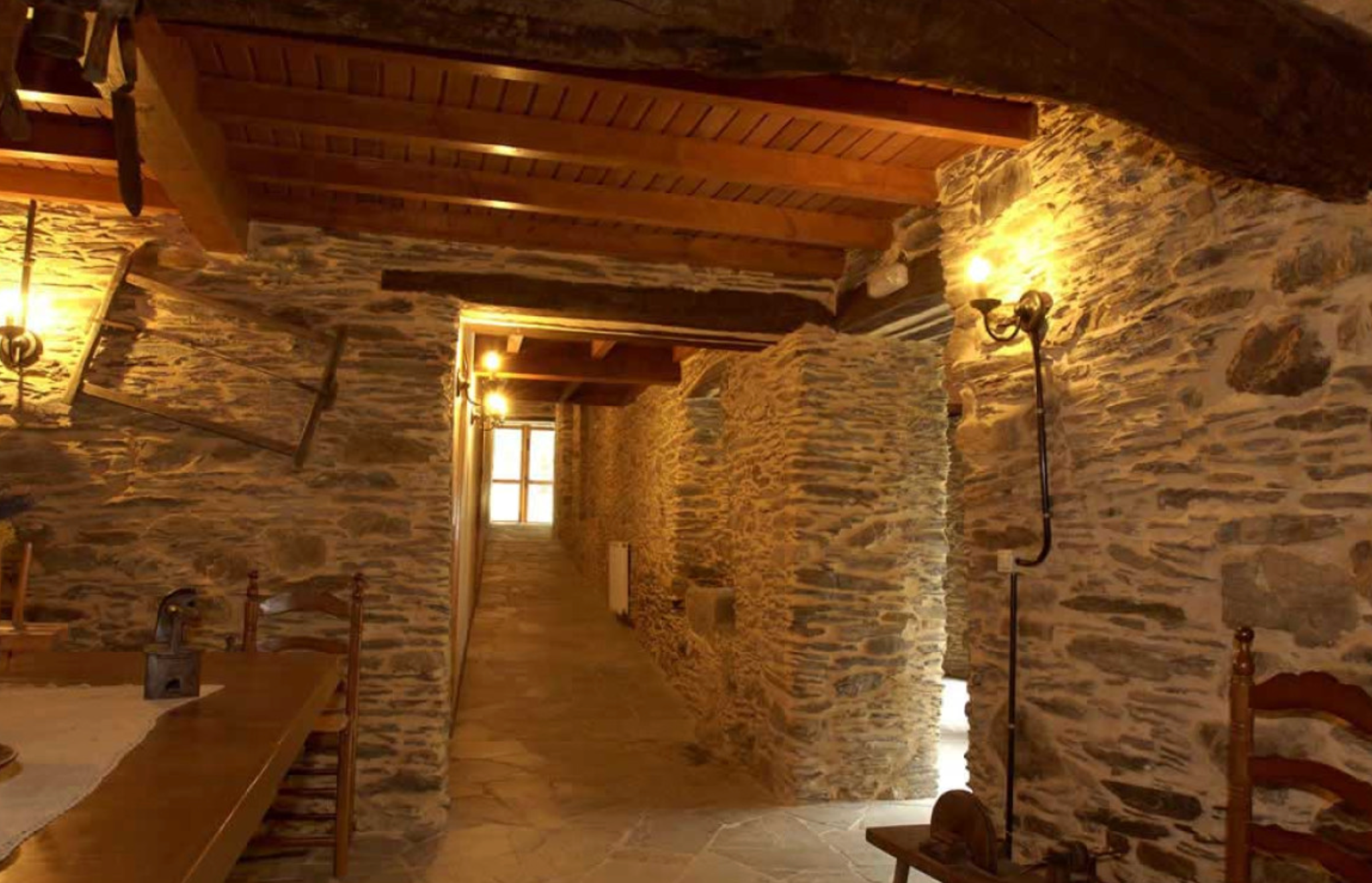 Mesa de madera y paso entre las estancias de piedra.
